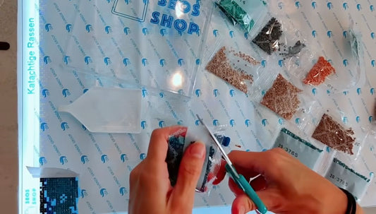 Kleurzakjes met codes, steentjes en een schudbakje naast een afgedekt diamond-paintingcanvas